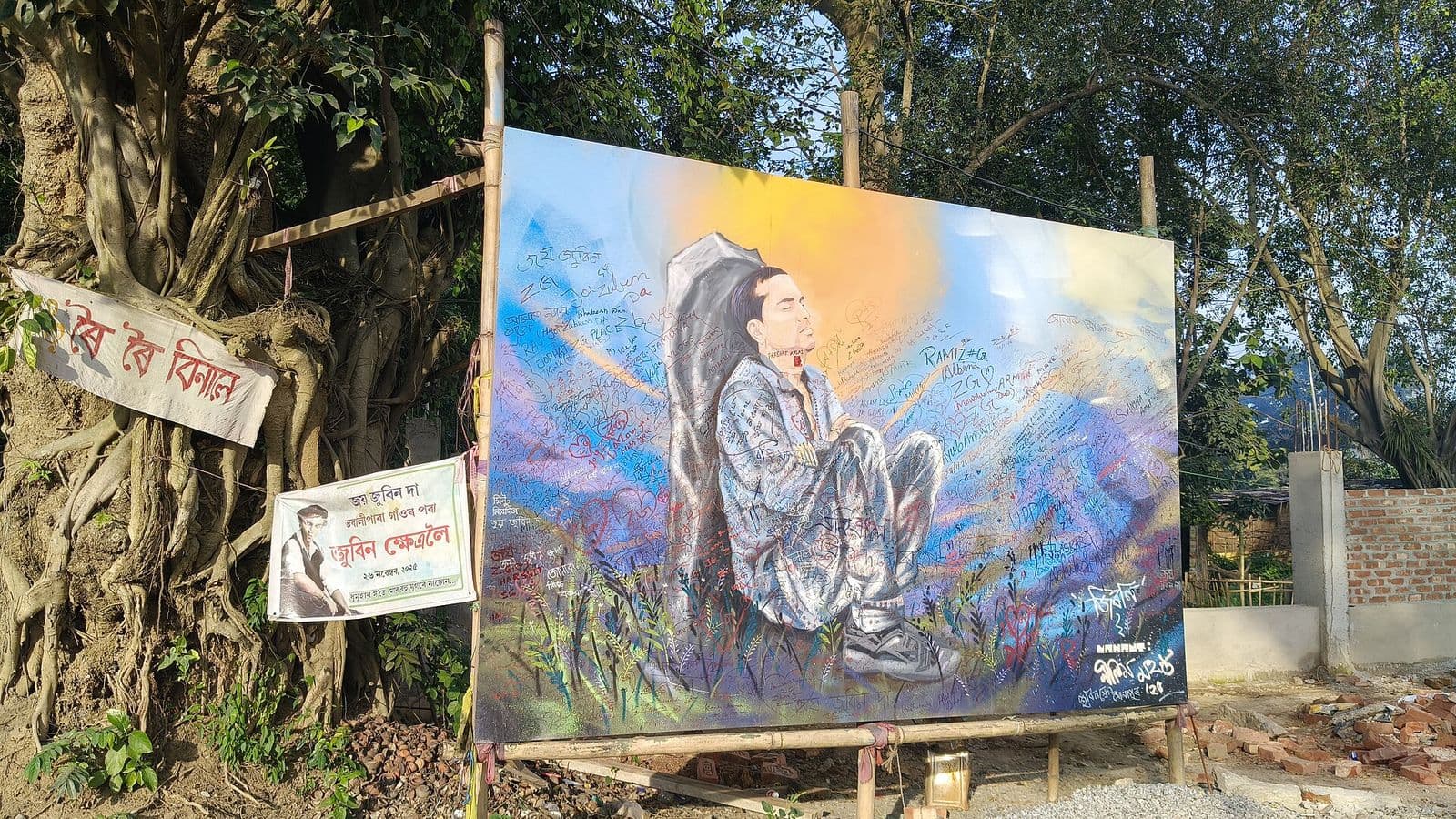 A large painted portrait of Zubeen Garg by Nilim Mahanta beside a tree