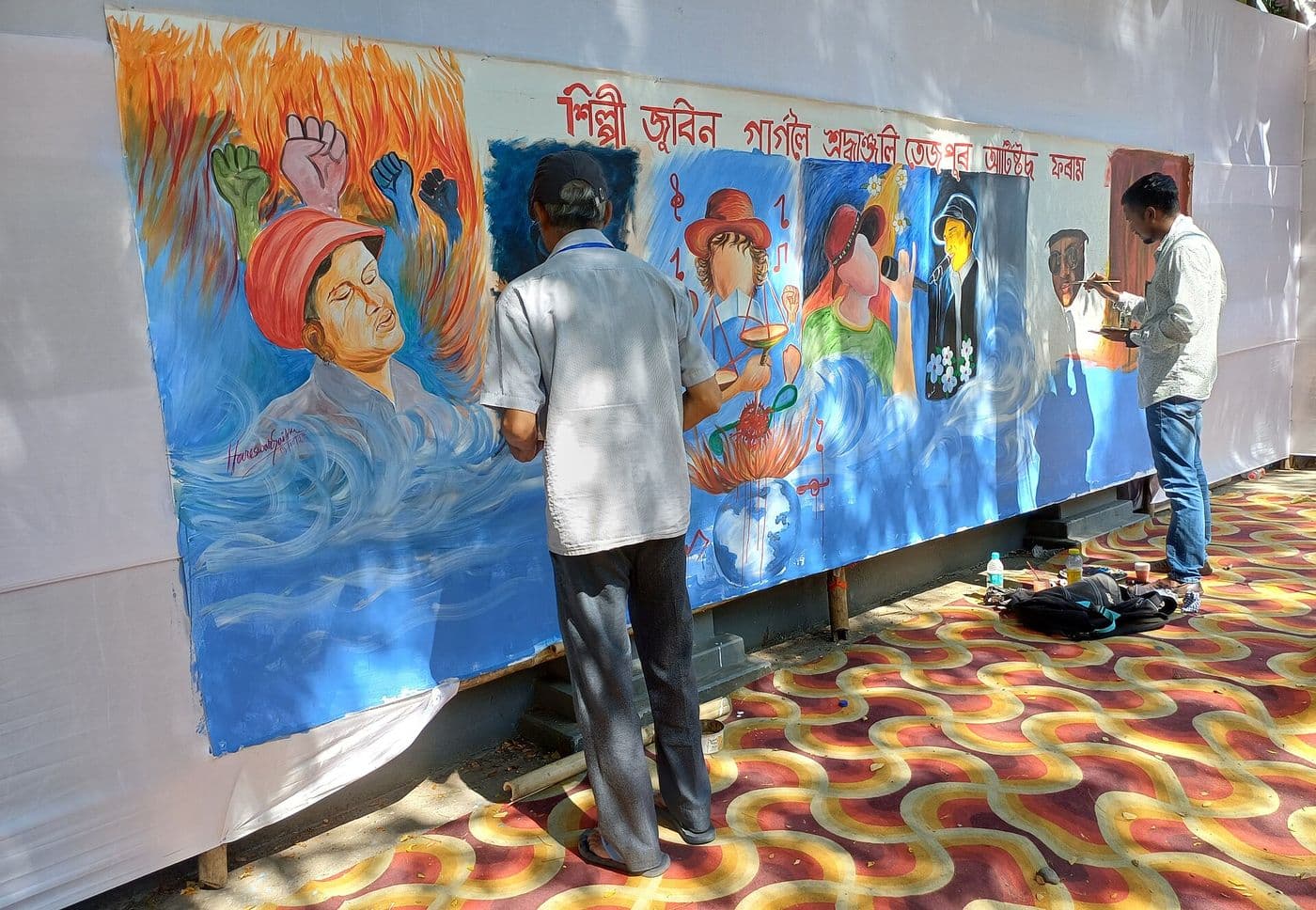 Artists painting a large tribute canvas to Zubeen Garg