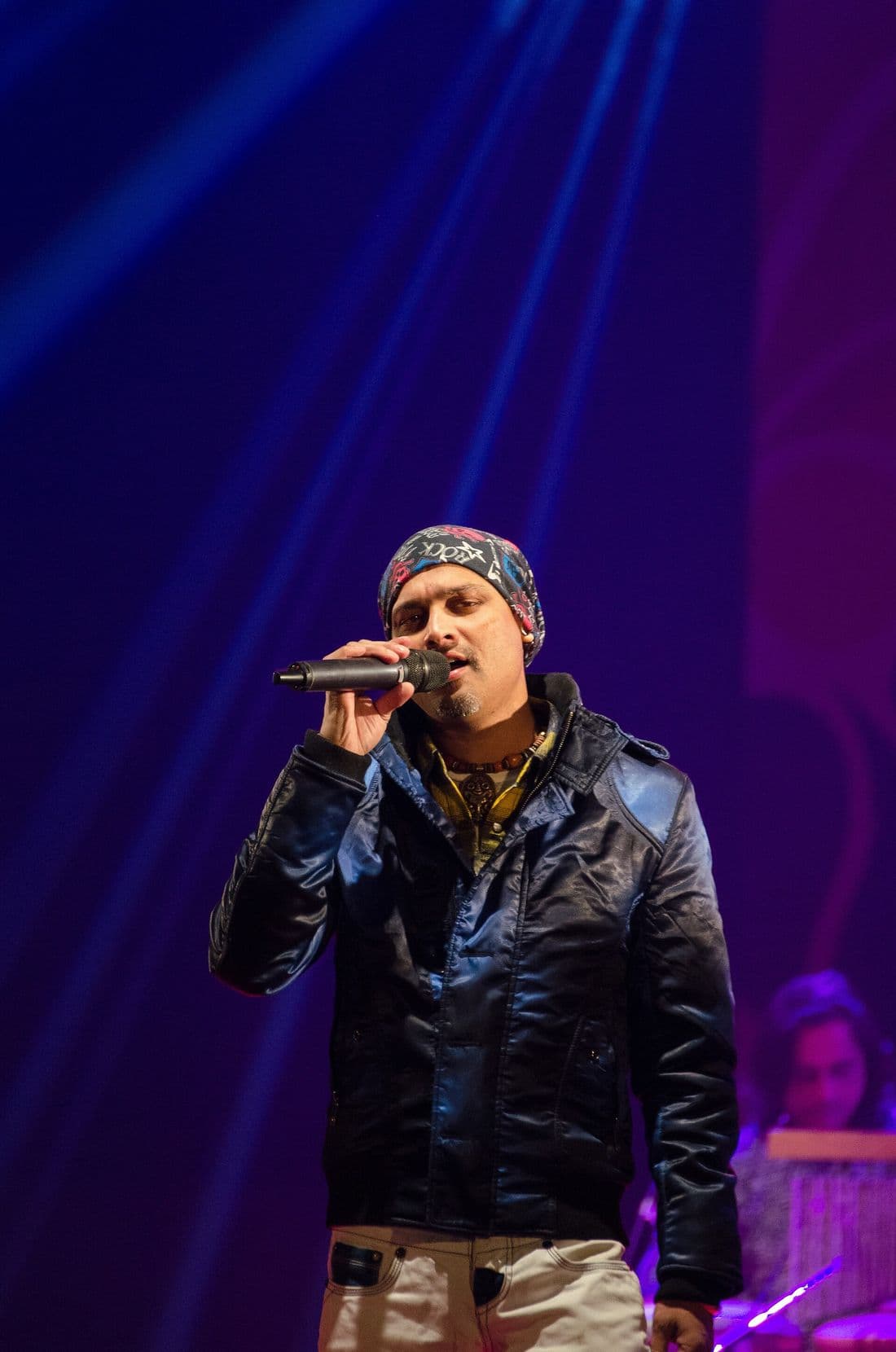 Zubeen Garg performing at a concert in a leather jacket and bandana